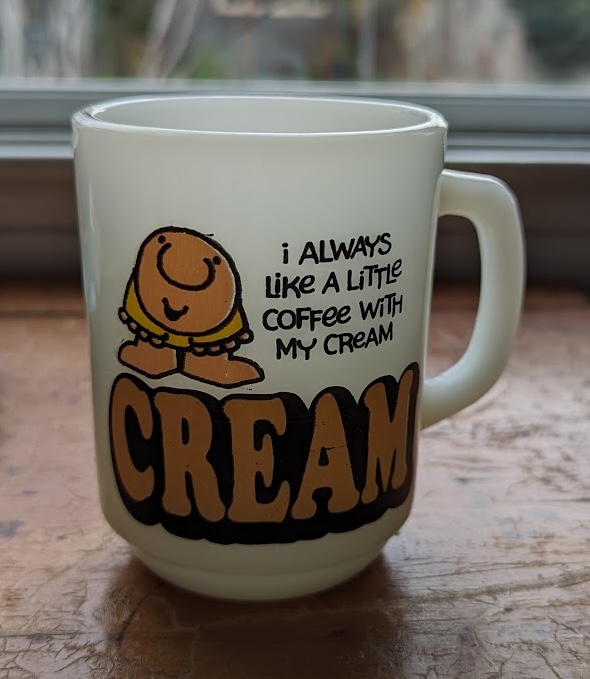 A coffee mug with a cartoon of Ziggy, saying: I always like a little coffee with my cream