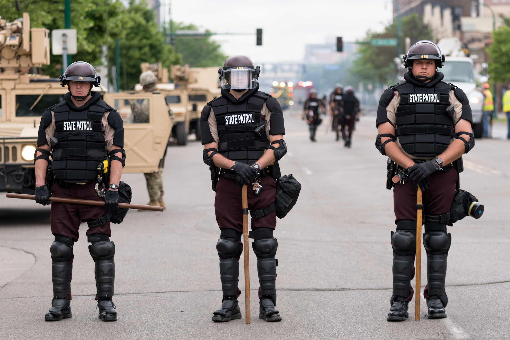 A line of uniformed, armored police carrying nightsticks